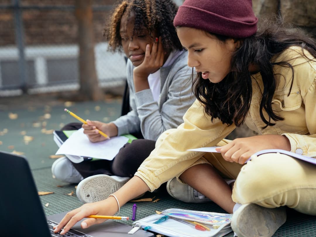 Duas estudantes adolescentes estudando juntas com notebook e cadernos