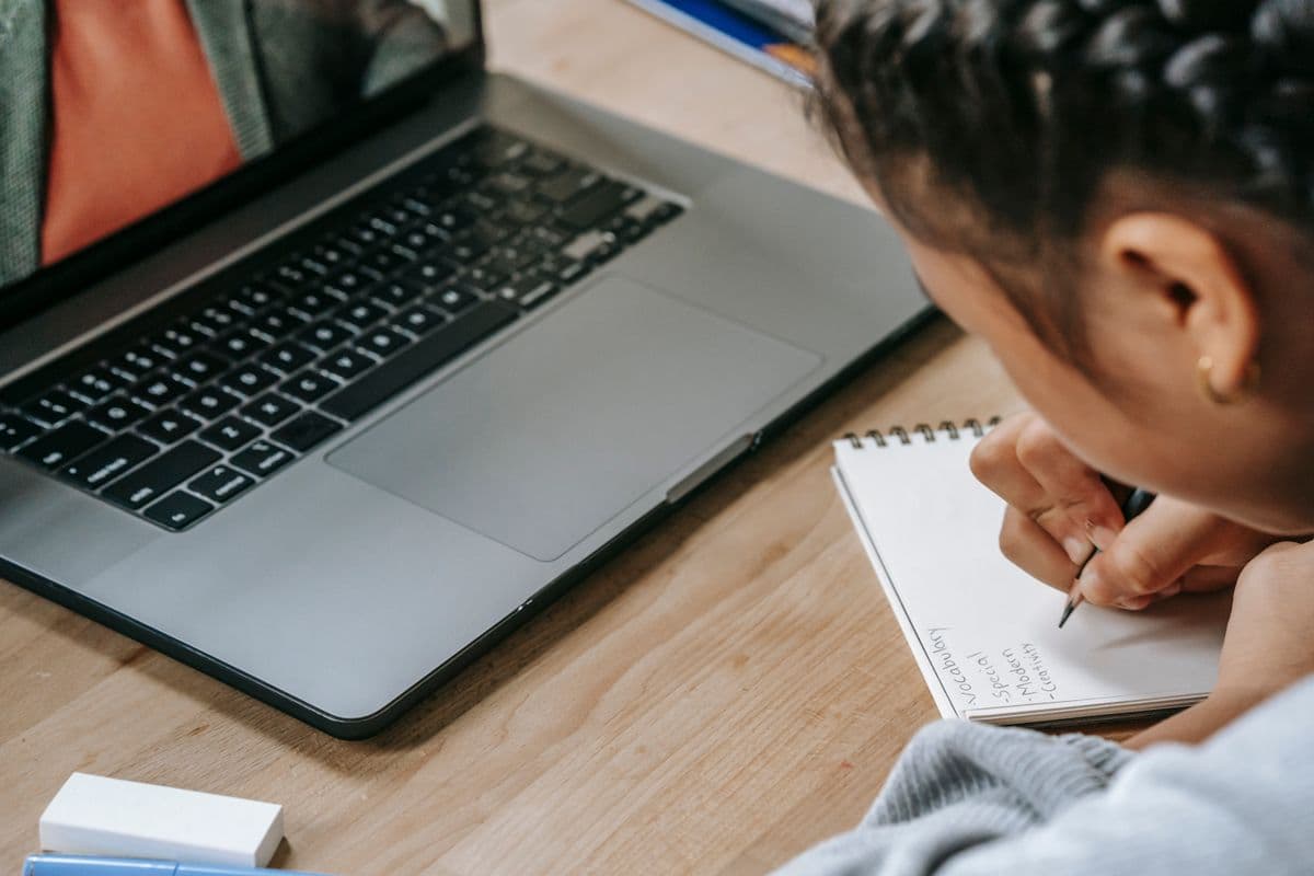 Estudante fazendo anotações durante uma aula on-line